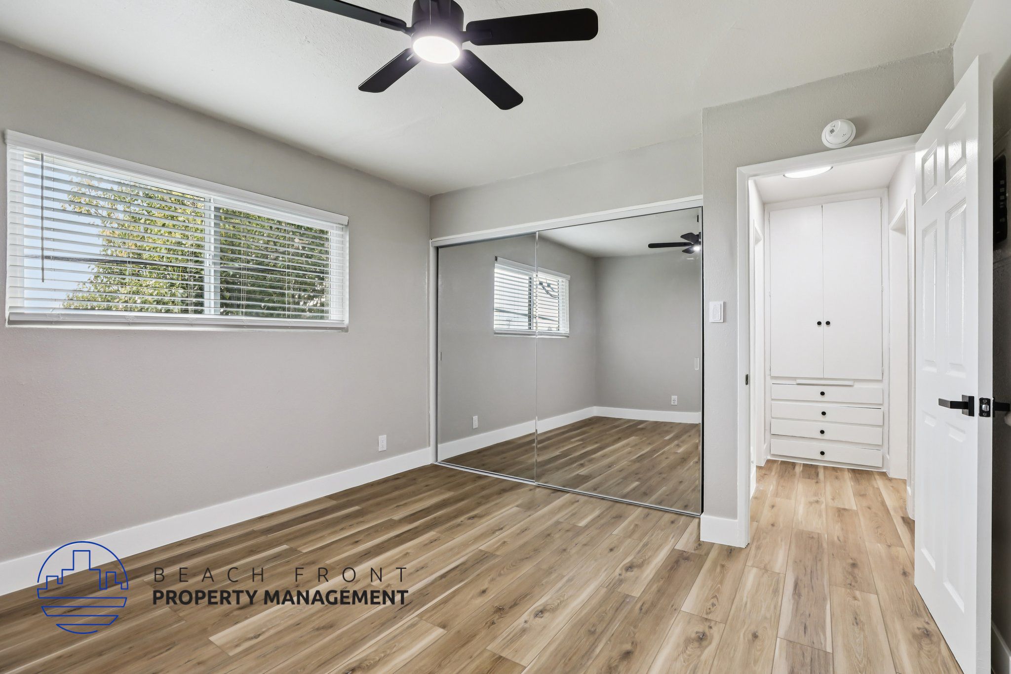A room with a ceiling fan and wooden flooring.